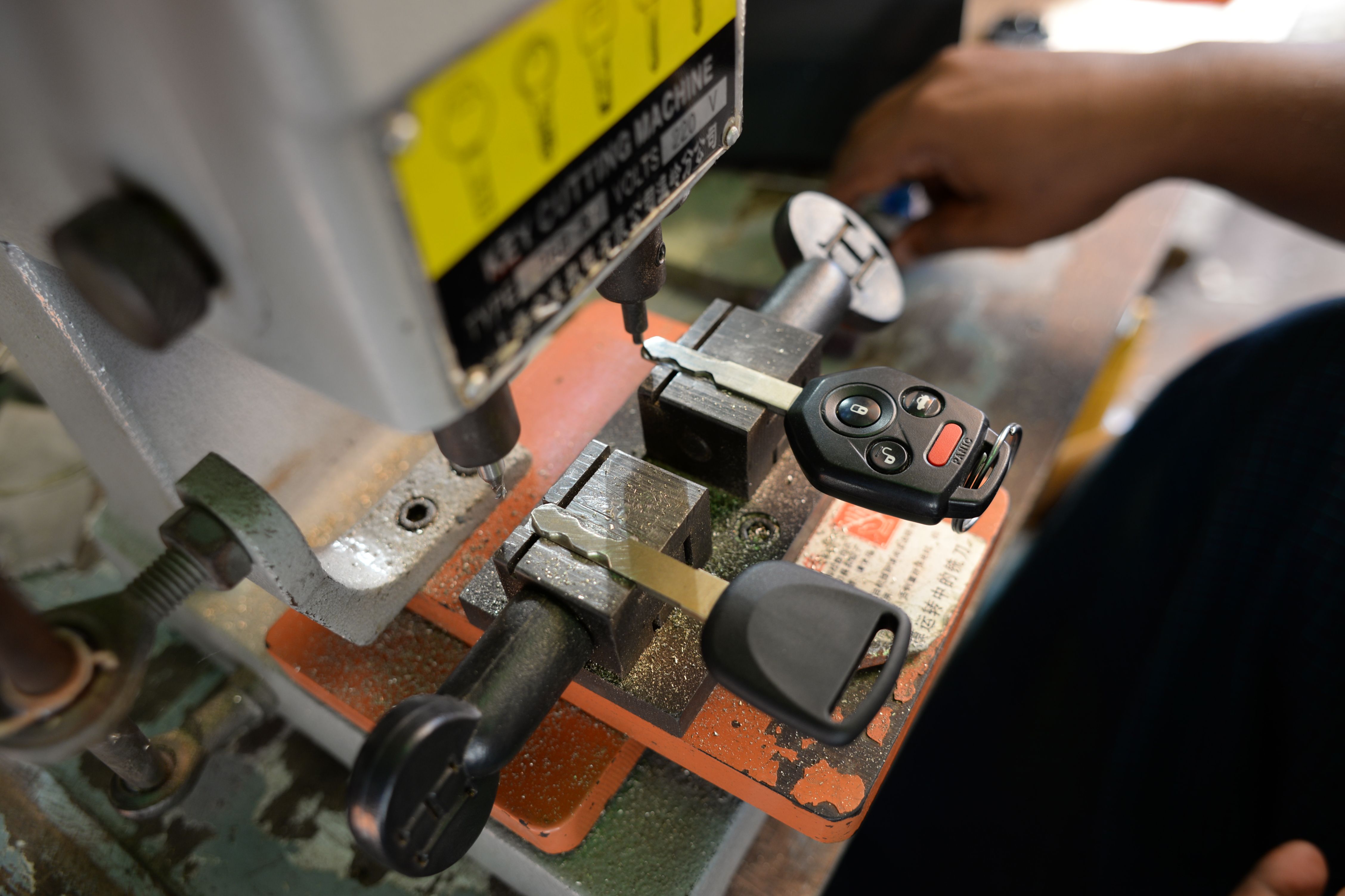 Les mains d'un serrurier guident une clé sur la machine à tailler de l'atelier