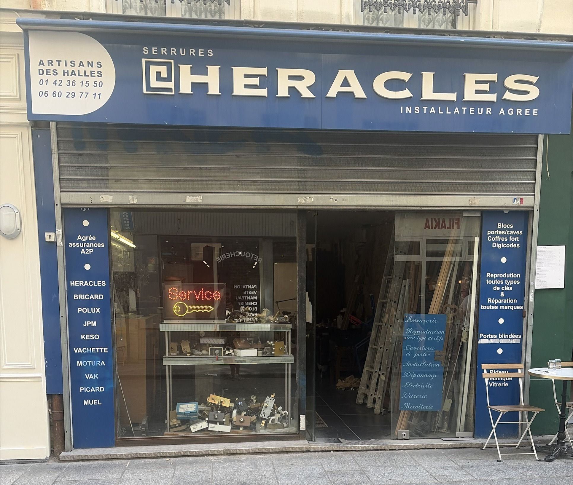 La devanture bleue d'Artisans des Halles, 12 rue Mandar : enseigne Serrures Héraclès installateur agréé, cartouche avec les deux numéros, vitrine de serrures et néon Service