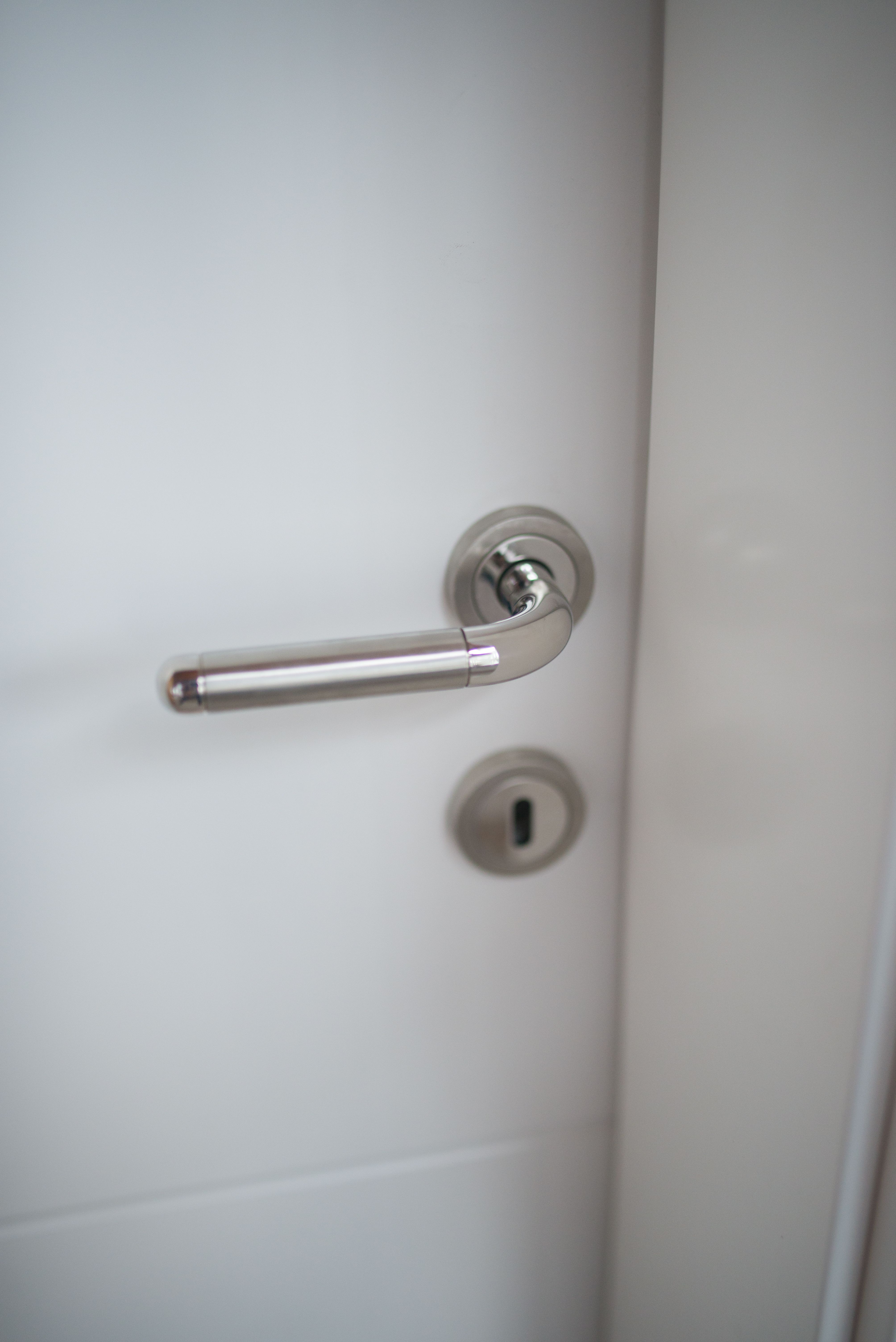 Poignée chromée et cylindre d'une porte d'entrée blanche